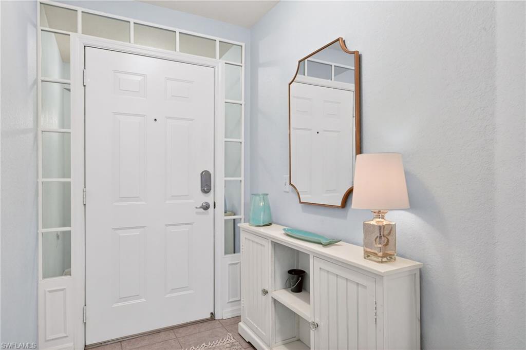 Entryway with a paneled white door, transom window, and sidelight windows