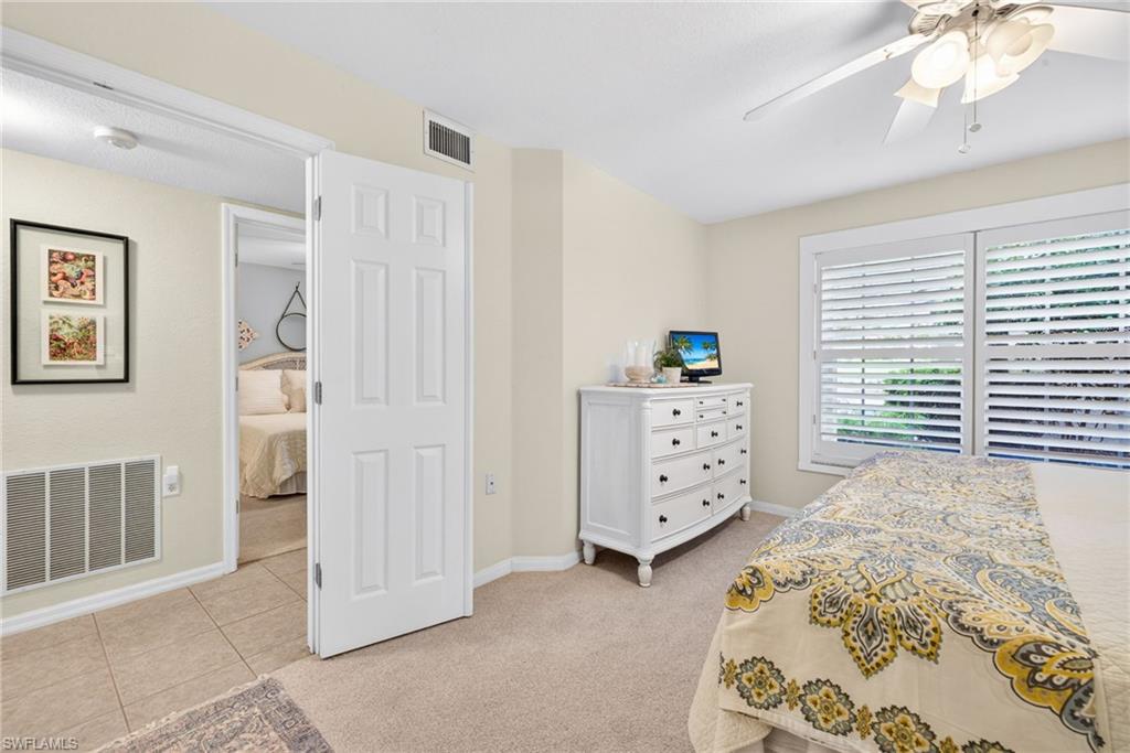 Primary Bedroom featuring plantation shutters, neutral-toned carpeting, and a ceiling fan with integrated lighting
