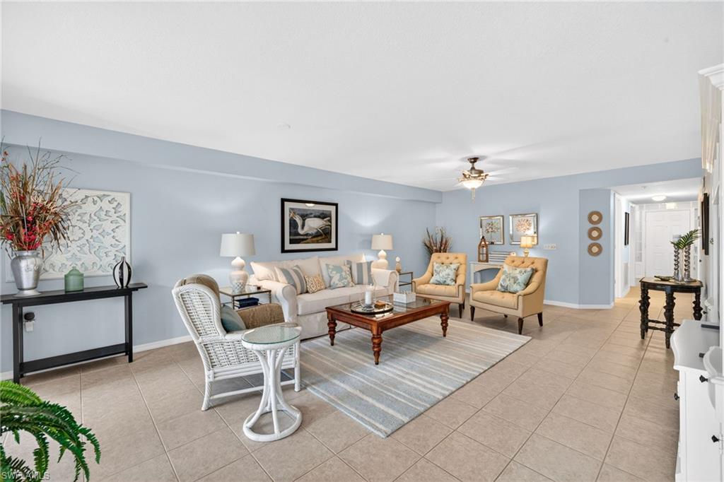Spacious living area featuring light-toned tile flooring, light blue wall paint, and a ceiling fan