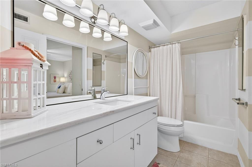 Bathroom featuring a white vanity with silver hardware, an integrated sink, and a full-width mirror with overhead lighting