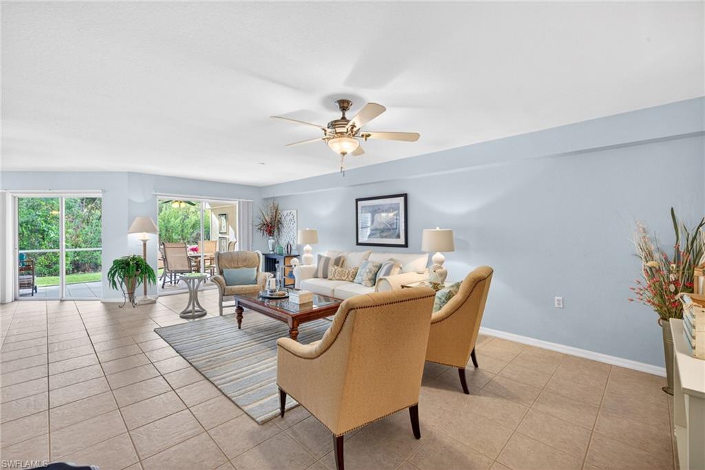 Spacious living area featuring neutral tile flooring, a ceiling fan with integrated lighting, and light blue wall tones