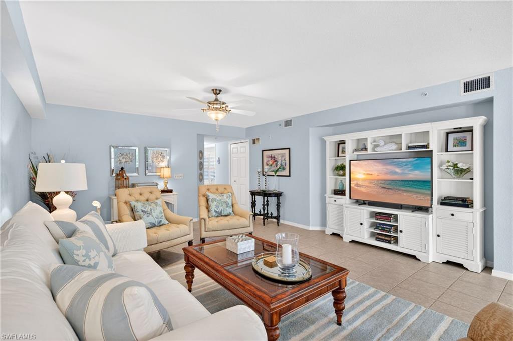 Expansive living area featuring tile flooring, a built-in media center with shelving, a ceiling fan with integrated lighting, and light blue wall tones