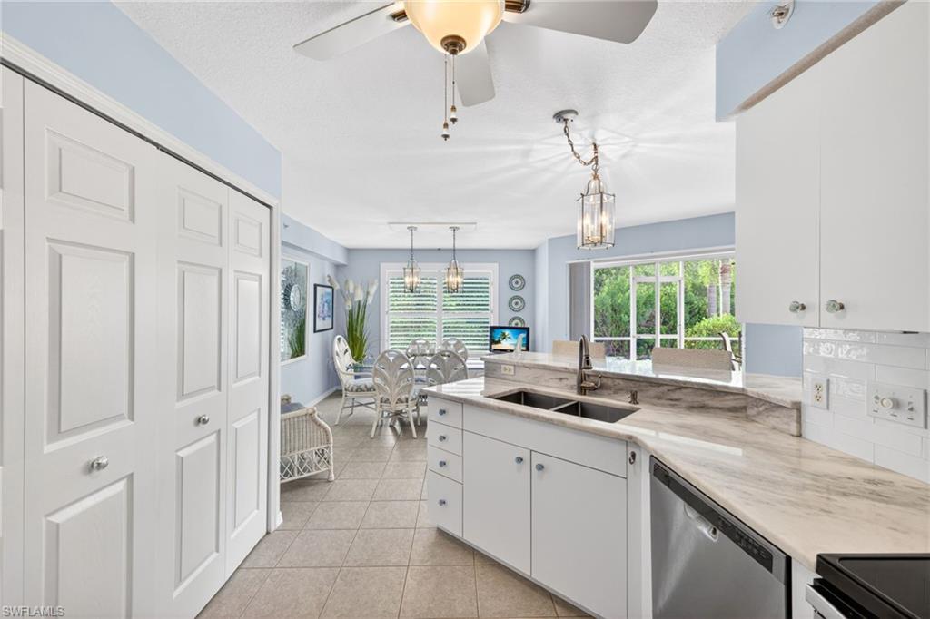 Kitchen featuring white cabinetry, a double basin sink, stainless steel dishwasher, light-toned countertop, and white subway tile backsplash