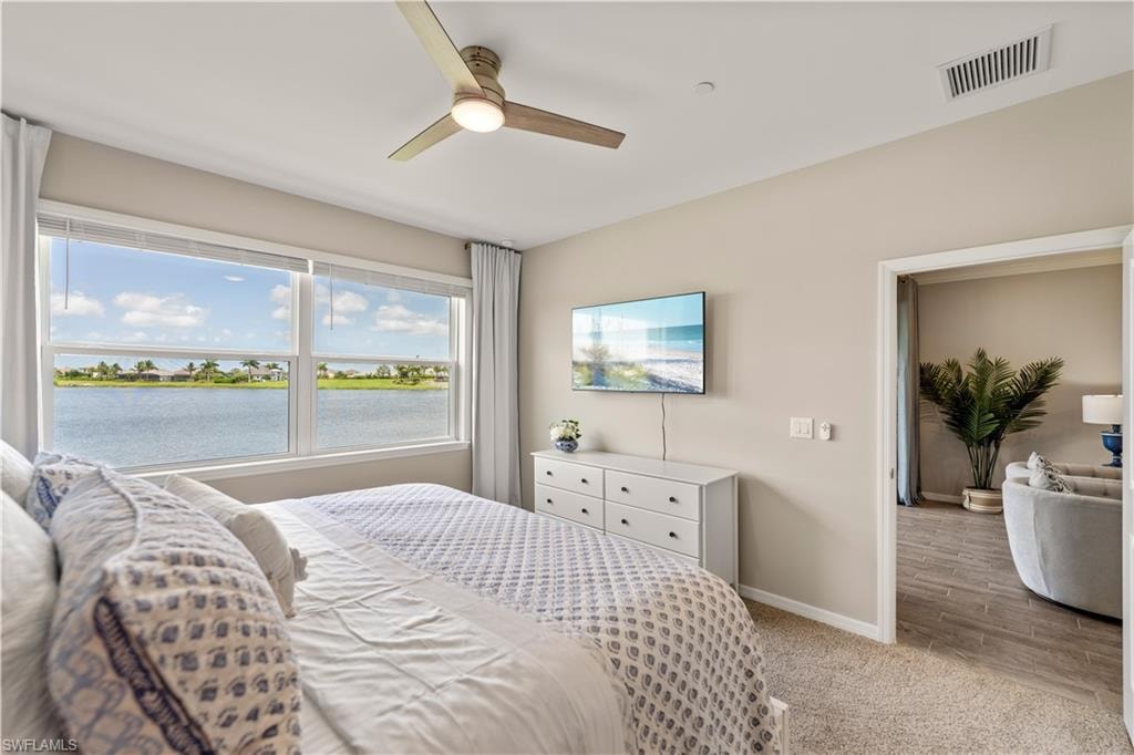 Bedroom with a water view, ceiling fan, and hardwood / wood-style floors