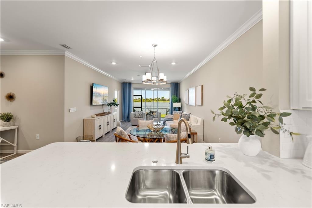Kitchen featuring tasteful backsplash, hardwood / wood-style floors, pendant lighting, sink, and ornamental molding