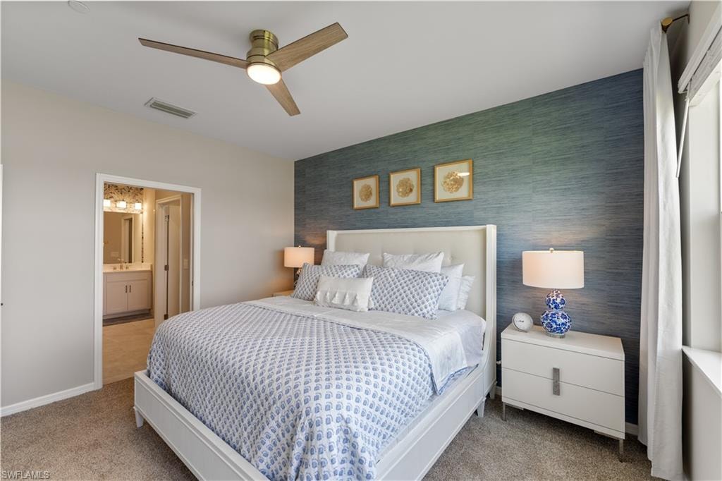 Carpeted bedroom featuring ceiling fan and connected bathroom