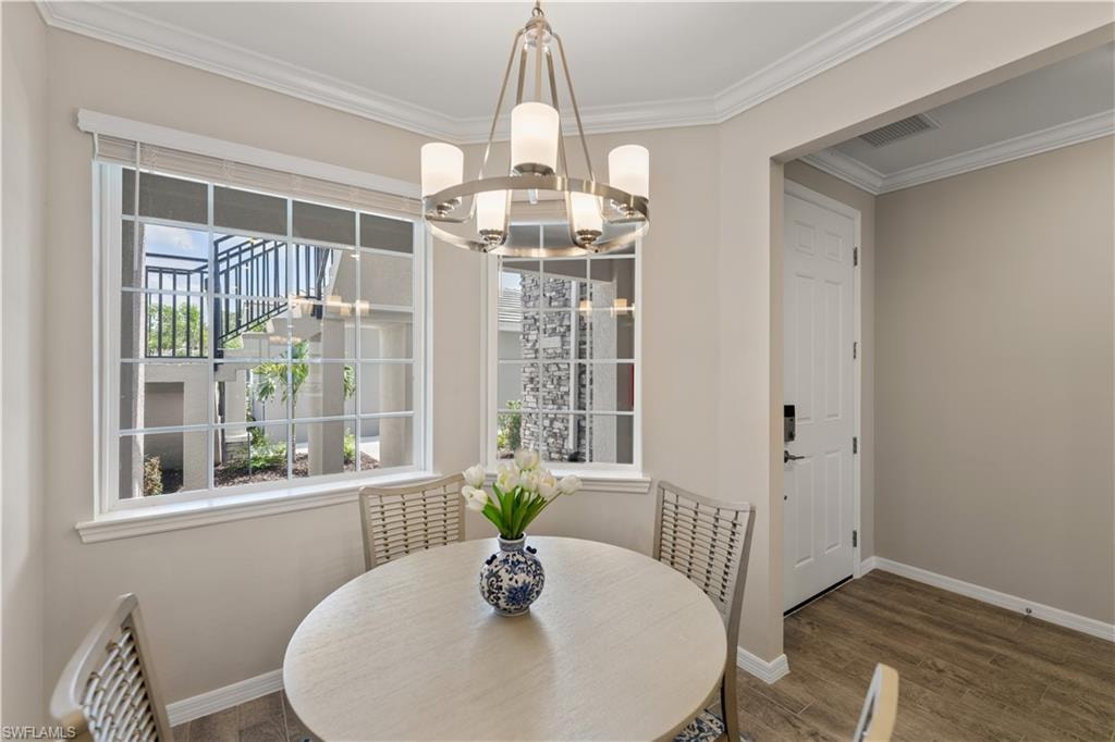 Dining area featuring hardwood / wood-style flooring, a notable chandelier, and ornamental molding