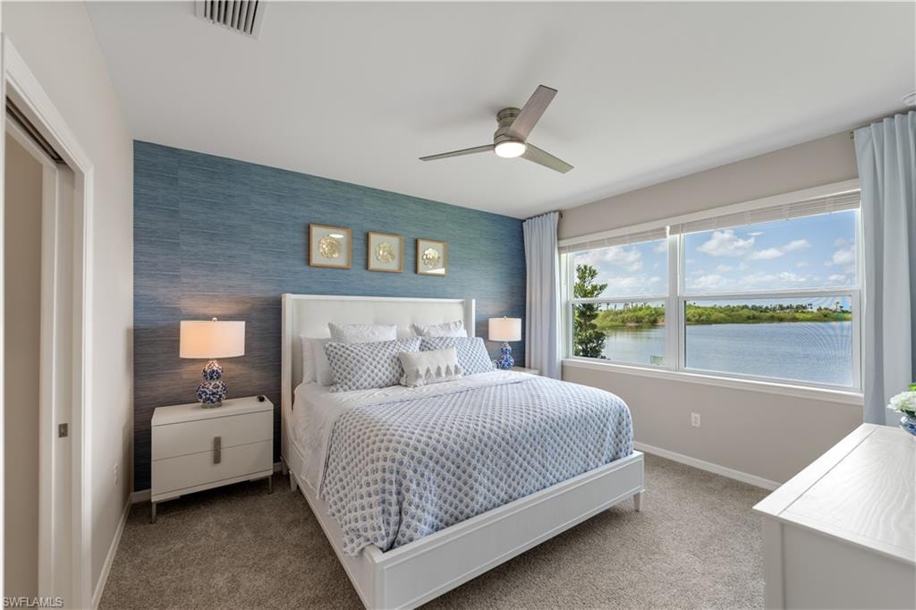 Bedroom with a closet, a water view, carpet, and ceiling fan