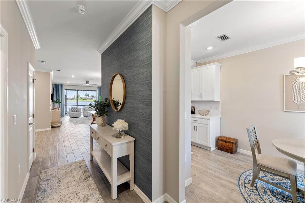 Hall with ornamental molding and light hardwood / wood-style floors