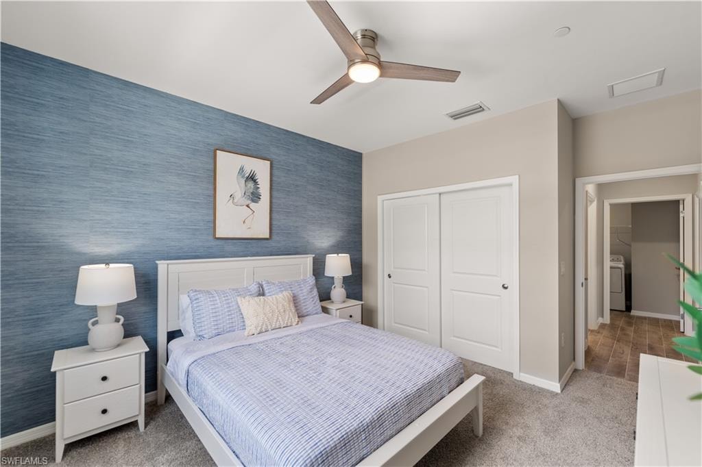 Carpeted bedroom featuring washer / dryer, ceiling fan, and a closet