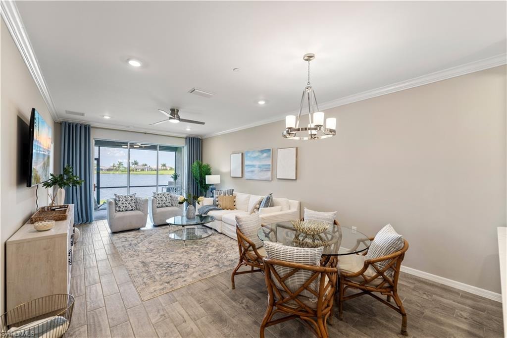 Dining room featuring ceiling fan with notable chandelier, wood-type flooring, and crown molding