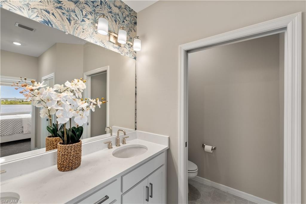 Bathroom featuring dual vanity, tile patterned floors, and toilet