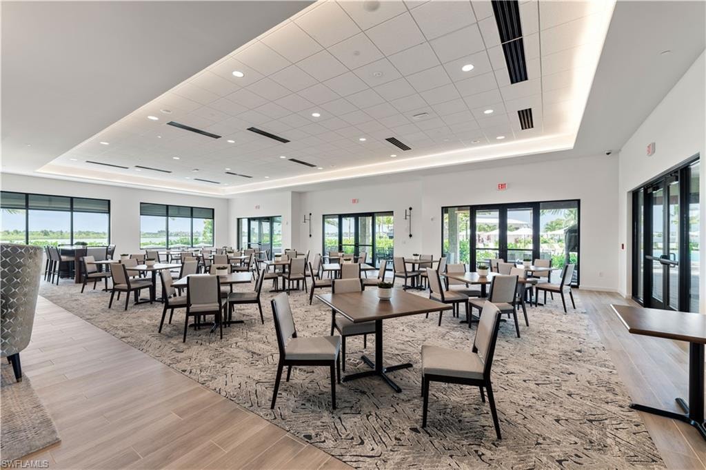 Dining room featuring a drop ceiling, french doors, light wood-type flooring, and a tray ceiling