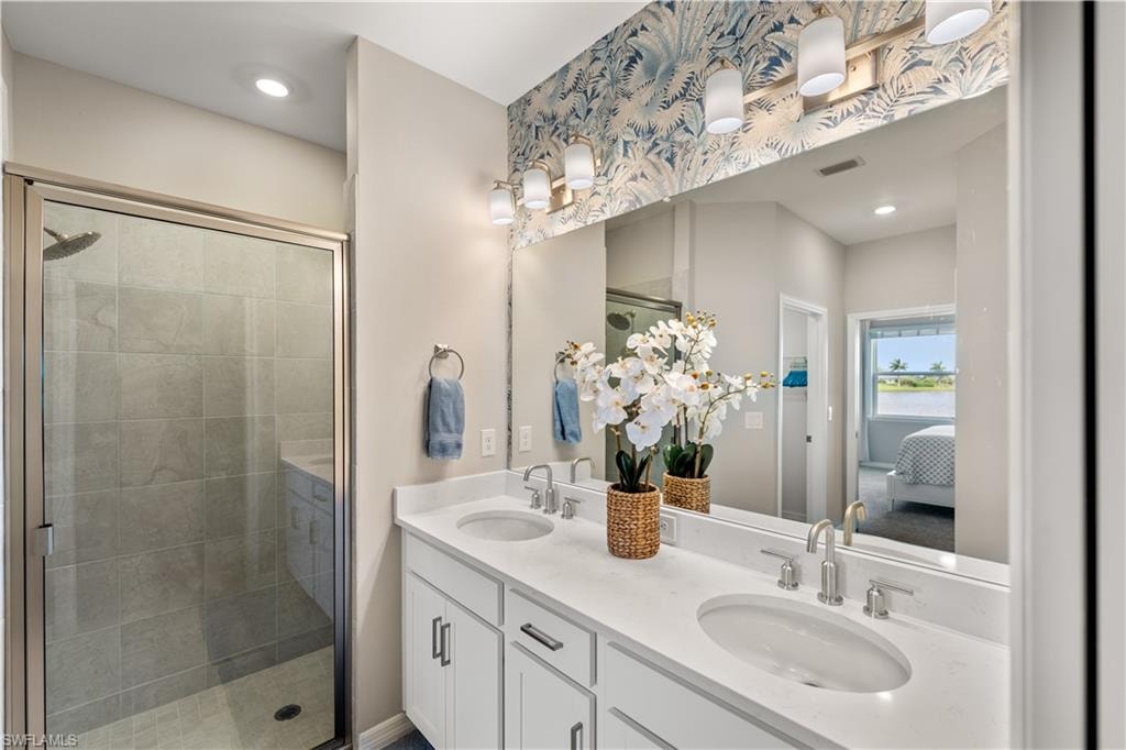 Bathroom featuring a shower with shower door and double sink vanity