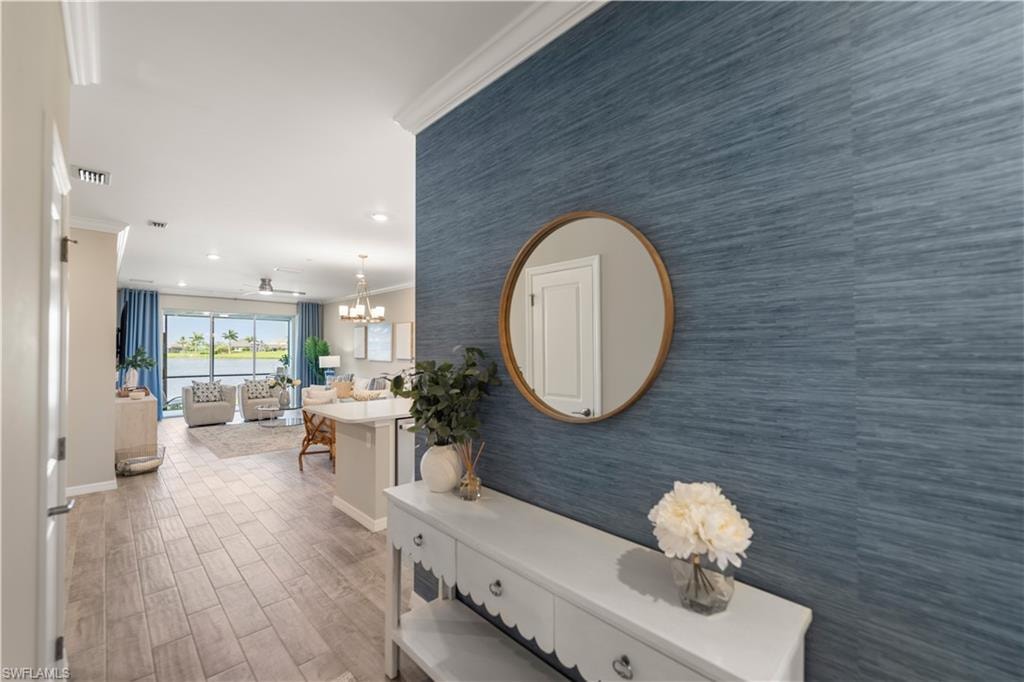Hallway with crown molding, hardwood / wood-style floors, and a chandelier