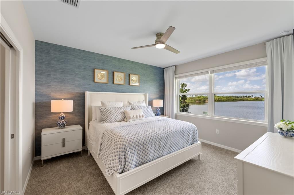 Carpeted bedroom featuring a water view, ceiling fan, and a closet