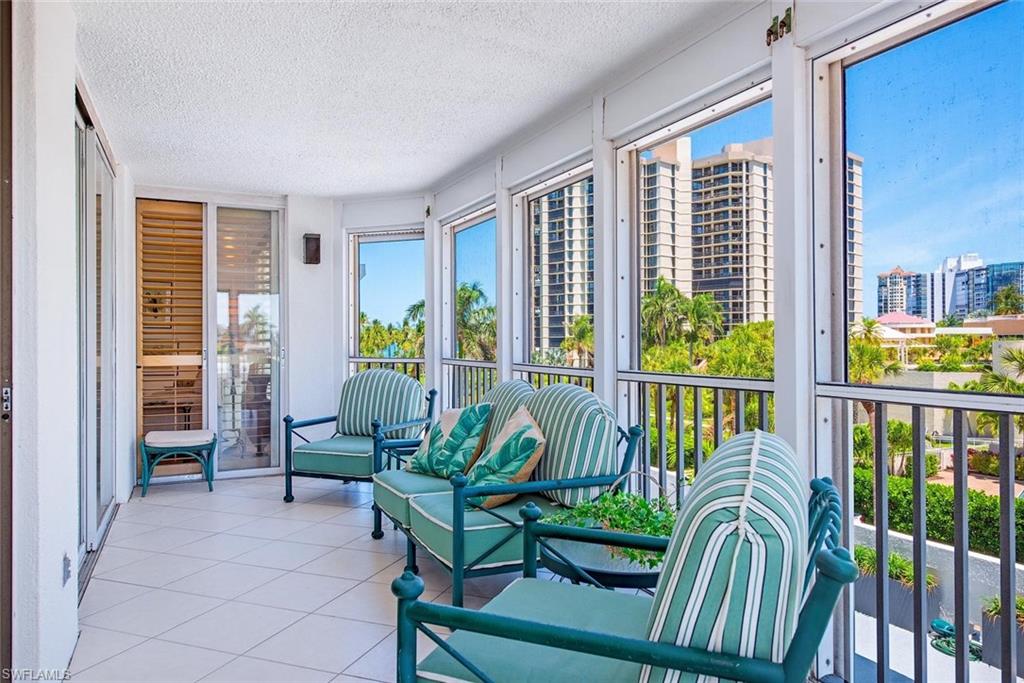 Enclosed balcony featuring large windows, sliding glass doors, white tiled flooring, and a flat white ceiling