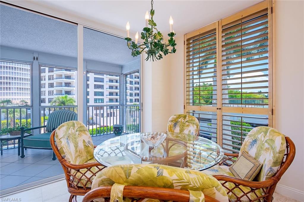 Interior space featuring a glass-top table, wood-finish plantation shutters, and a screened balcony