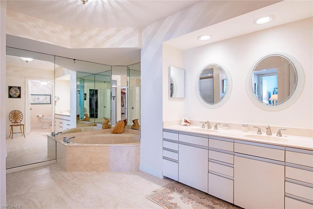 Bathroom featuring a double vanity with round mirrors and recessed lighting