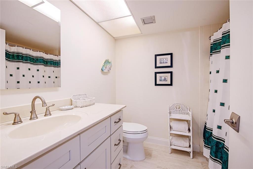 Bathroom featuring a single vanity with an integrated sink, brushed nickel faucet, and shaker-style cabinetry