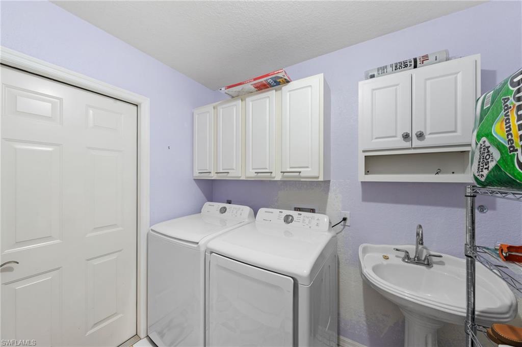 Dedicated laundry space featuring a pedestal sink with a chrome faucet, wall-mounted cabinetry, and a paneled door