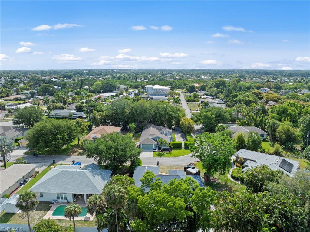 Expansive residential area featuring numerous single-story homes, mature trees, and a clear blue sky overhead