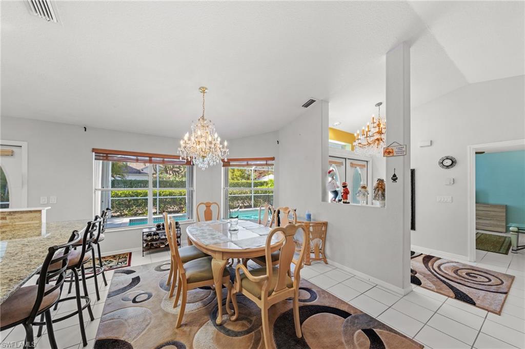 Dining area featuring a crystal chandelier, tile flooring, and multiple windows offering views of the exterior pool