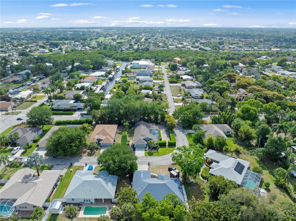 Aerial perspective of a residential neighborhood featuring established homes with varying rooflines, some properties include private swimming pools, and mature landscaping
