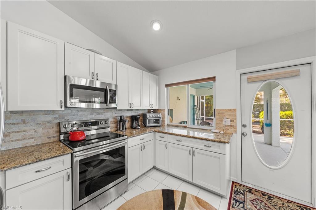Kitchen featuring white cabinetry, stone-finish countertops, stainless steel appliances, and a tiled backsplash