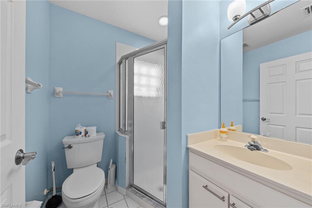 Bathroom featuring a shower stall with frosted glass, a single vanity with an integrated sink, a wall-mounted mirror, and a toilet
