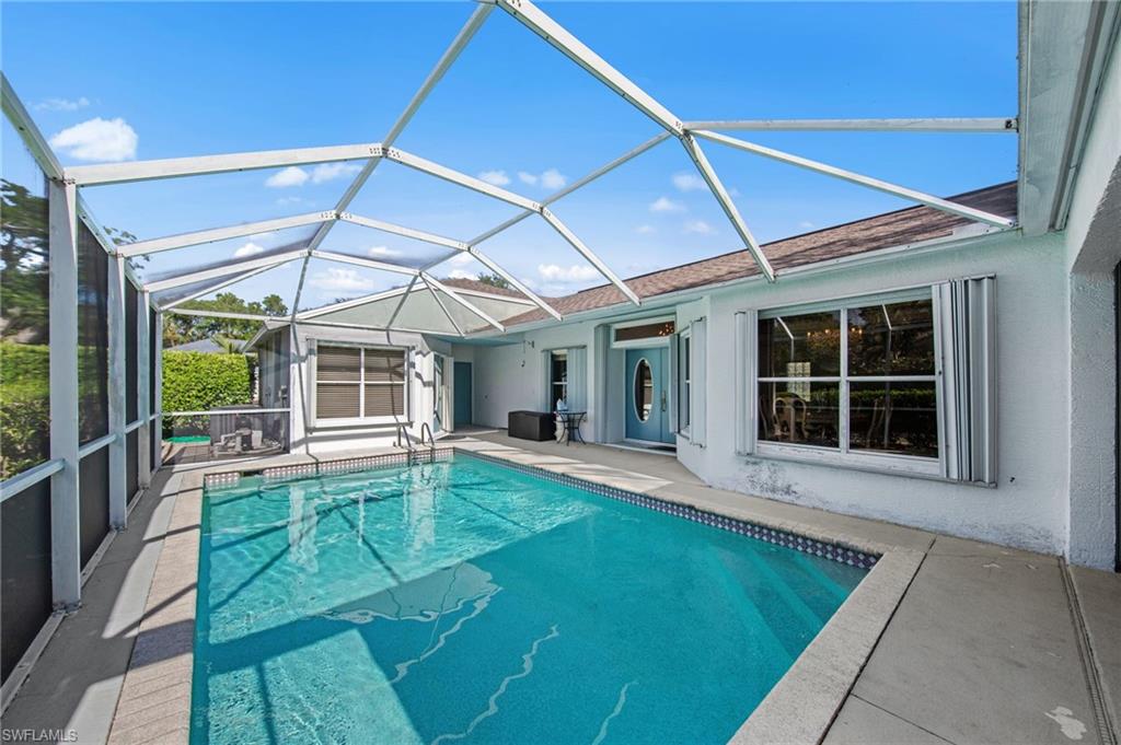 Screened swimming pool enclosure featuring a rectangular pool with concrete decking