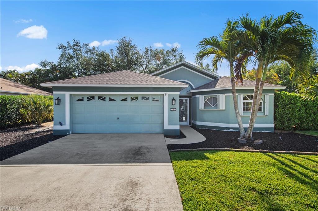 Single-story residence featuring a two-car garage with decorative windows, a curved concrete walkway, and a stucco exterior