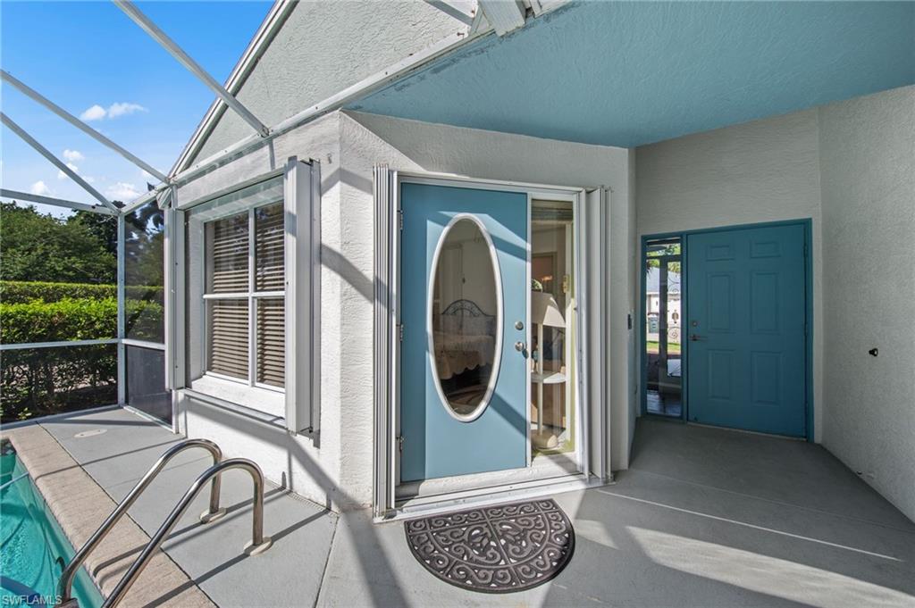 Poolside entry featuring a blue oval glass front door, covered patio, screened enclosure, and a turquoise painted ceiling