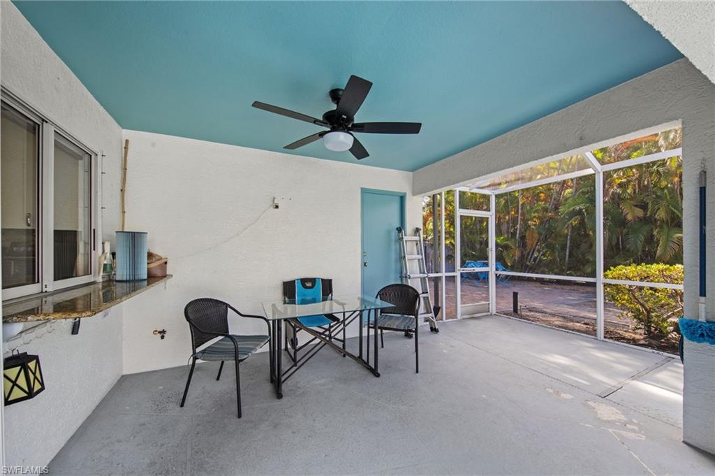 Screened patio featuring a ceiling fan, a pass-through window with a granite-look countertop, a light blue ceiling, and an exterior door