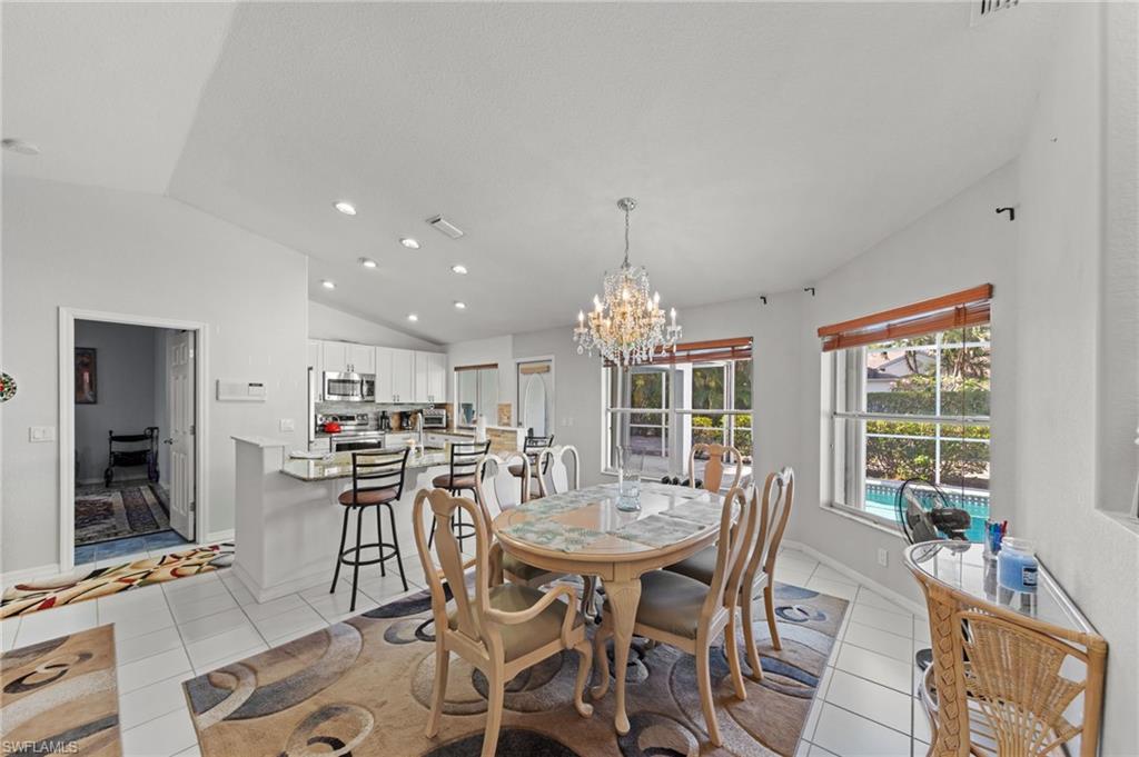 Open-concept dining area featuring a crystal chandelier, tiled flooring, and multiple windows