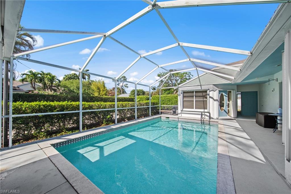 Screened-in pool area featuring a rectangular pool with tiled coping, a spacious concrete deck, and a screened enclosure