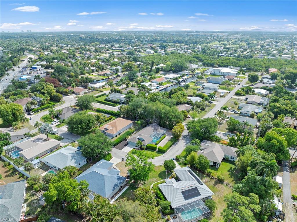 Expansive aerial showcasing a residential neighborhood with diverse roofing styles, mature landscaping, and an organized street grid