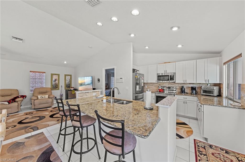 Kitchen featuring light-toned cabinetry, stainless steel appliances, and granite countertops