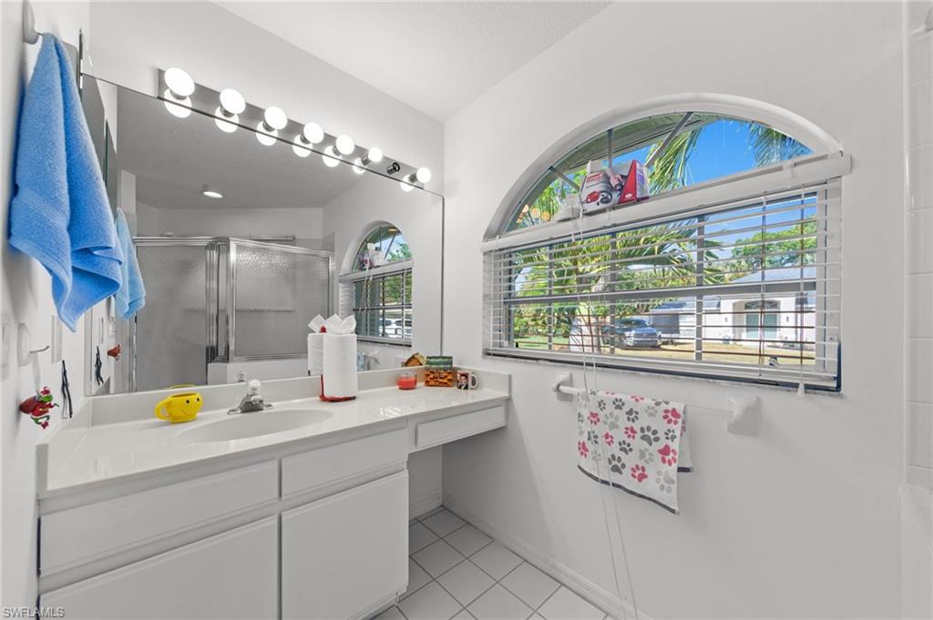 Vanity with integrated sink, white countertop, and extensive mirror with strip lighting