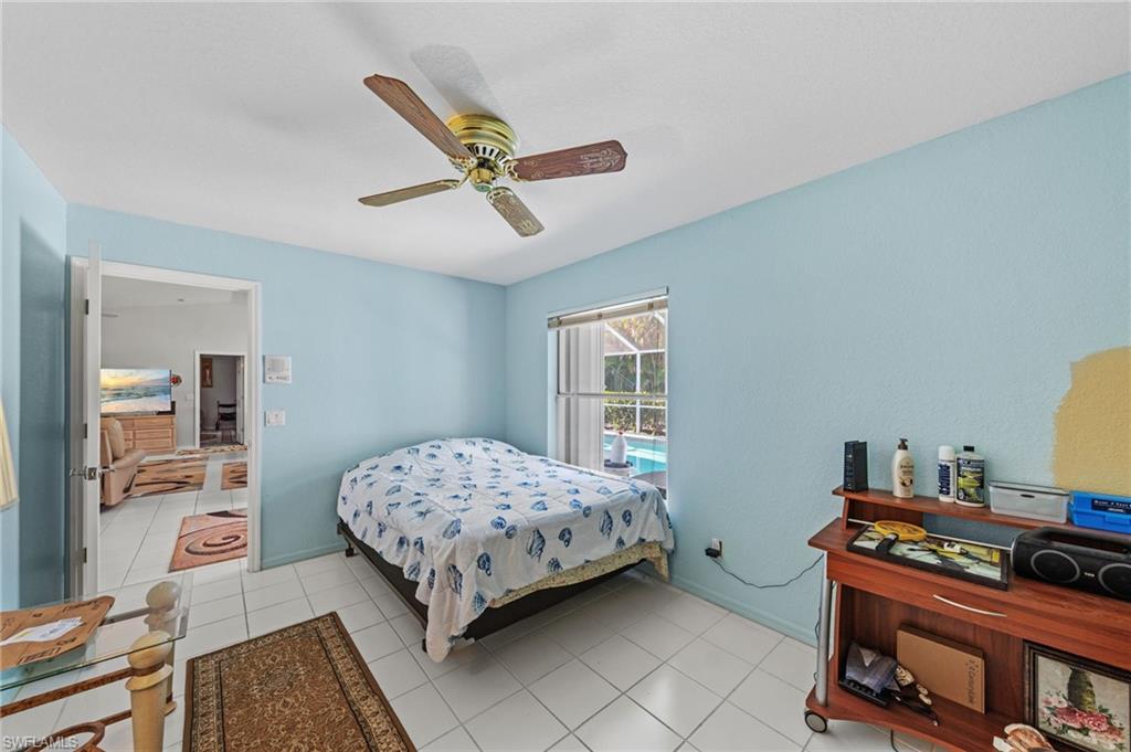 Room featuring light blue walls, white tile flooring, and a ceiling fan with wood-finish blades