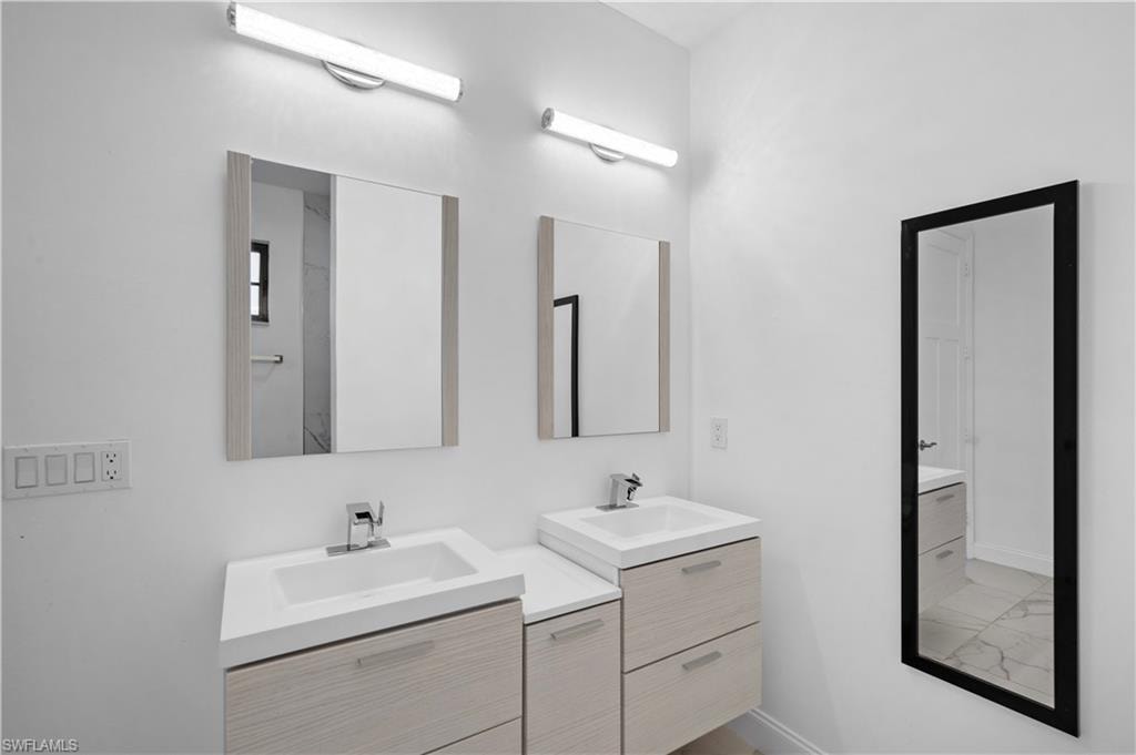 Dual vanity featuring light wood-finish cabinetry, integrated white sinks, and chrome faucets