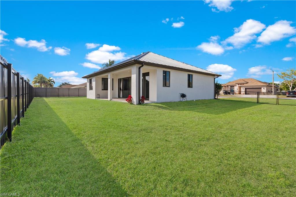 Expansive green lawn with a white stucco exterior and a metal roof