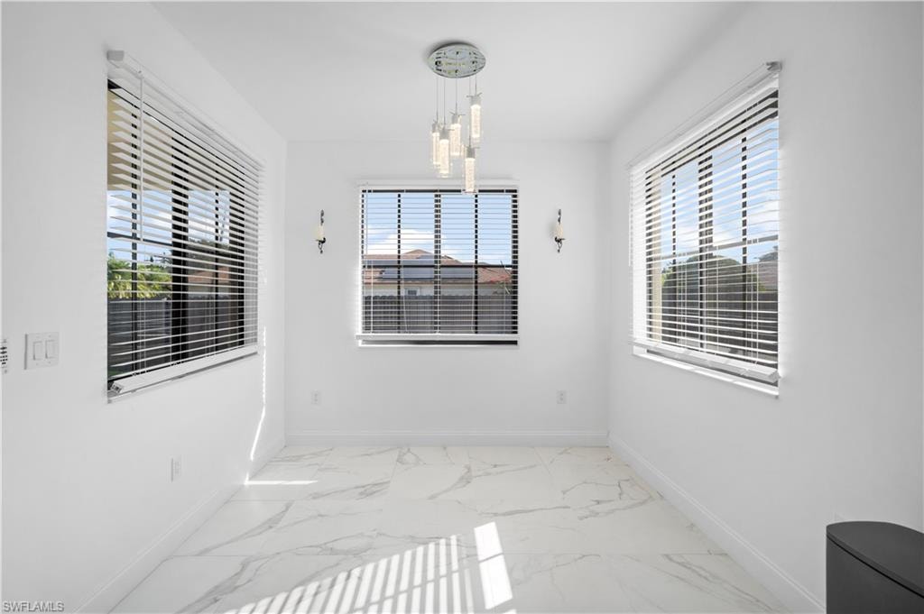 Bright room featuring white walls, large windows with horizontal blinds, and a contemporary chandelier