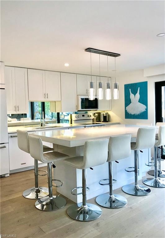 Kitchen featuring light countertops, light wood finished floors, electric stove, and white cabinets