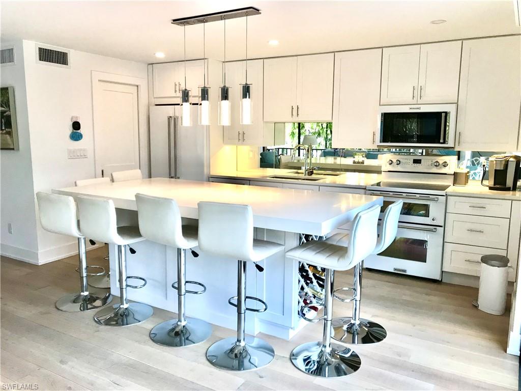 Kitchen featuring range with two ovens, a sink, white cabinets, high end fridge, and a kitchen bar