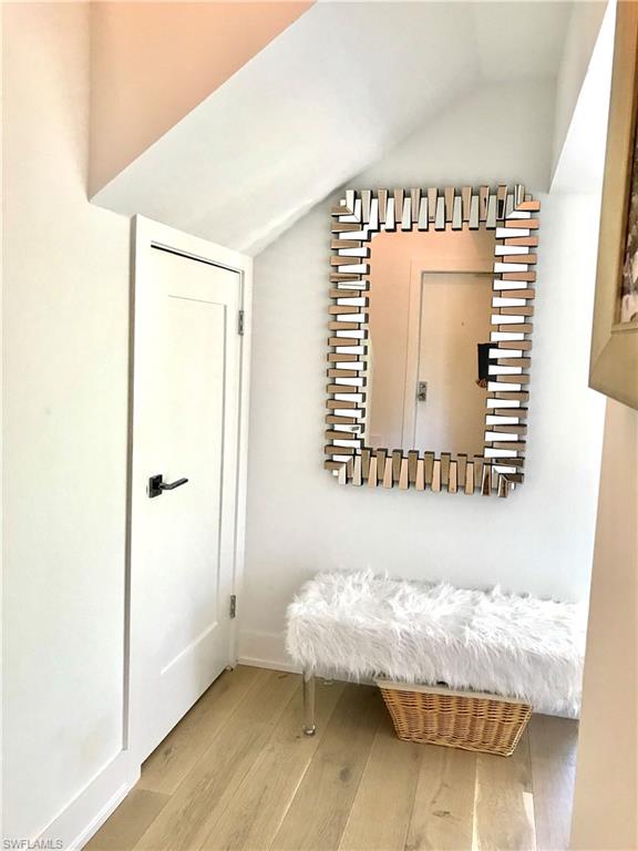 Corridor featuring light wood-type flooring, lofted ceiling, and baseboards