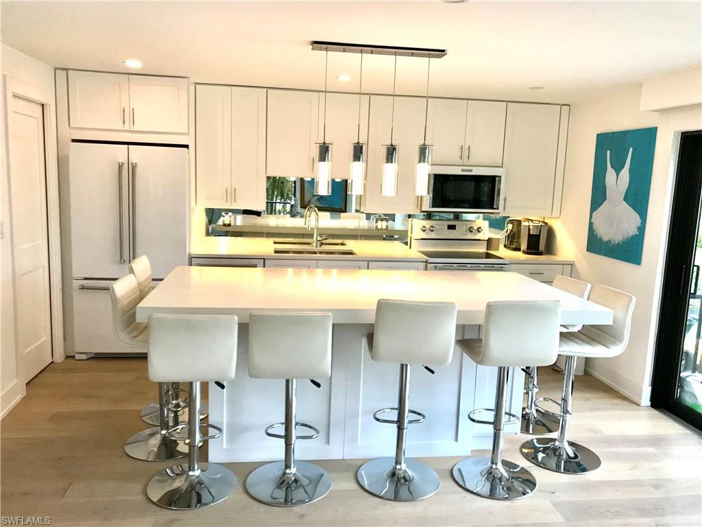 Kitchen featuring a kitchen bar, white cabinets, a sink, and electric range oven
