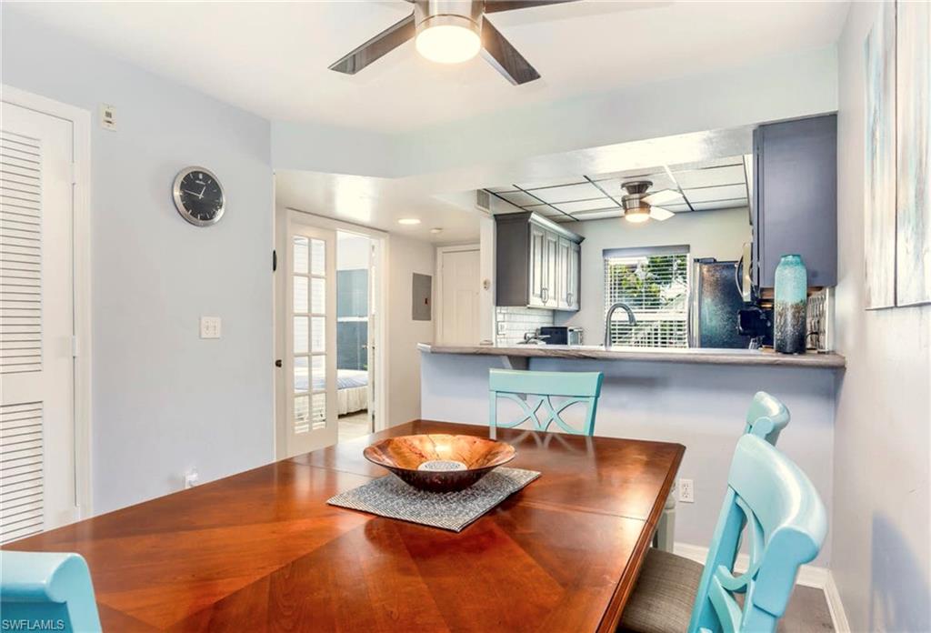 Dining area featuring a wood-finish table, ceiling fan with integrated lighting, and a pass-through opening to the kitchen