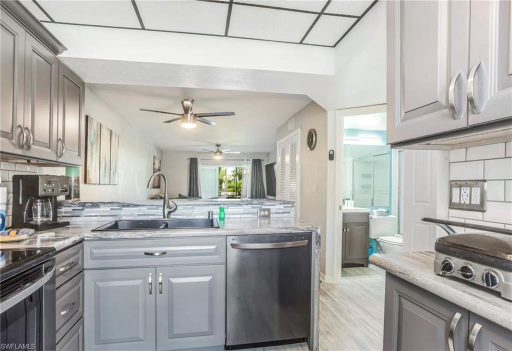 Kitchen featuring gray cabinetry, stainless steel appliances, a subway tile backsplash, and light-toned countertops