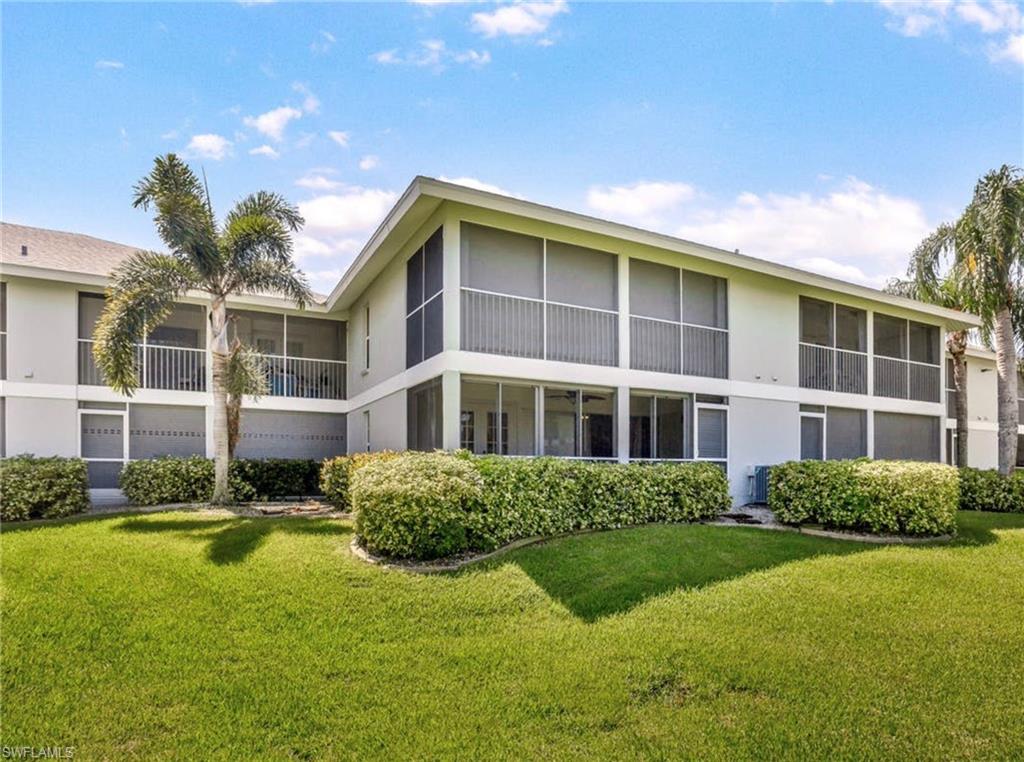 Rear elevation with multiple screened lanais and balconies, featuring mature landscaping and a well-kept lawn